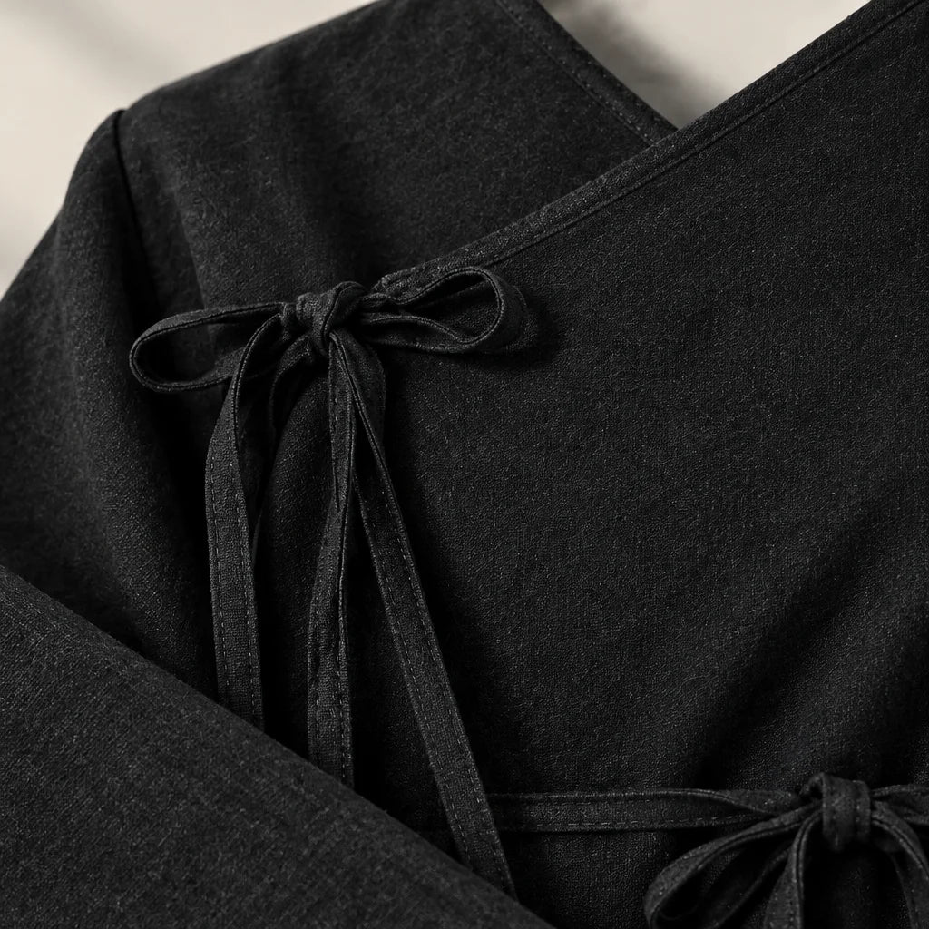 A close macro photograph of the exact black top from the reference, filling the square frame with a