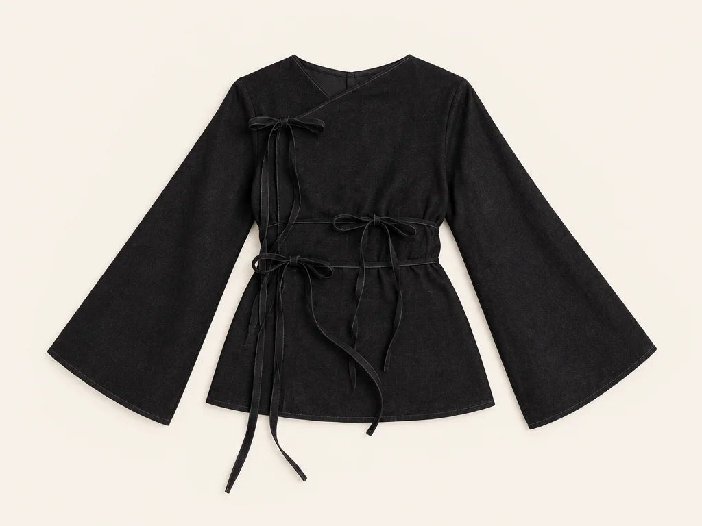 An overhead fashion product photograph of the exact black asymmetric top from the reference, laid fl
