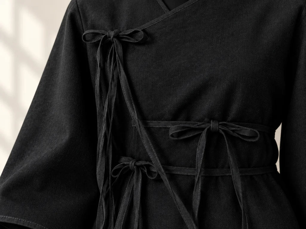 A close macro photograph of the exact black top from the reference, cropped from shoulder to hip wit